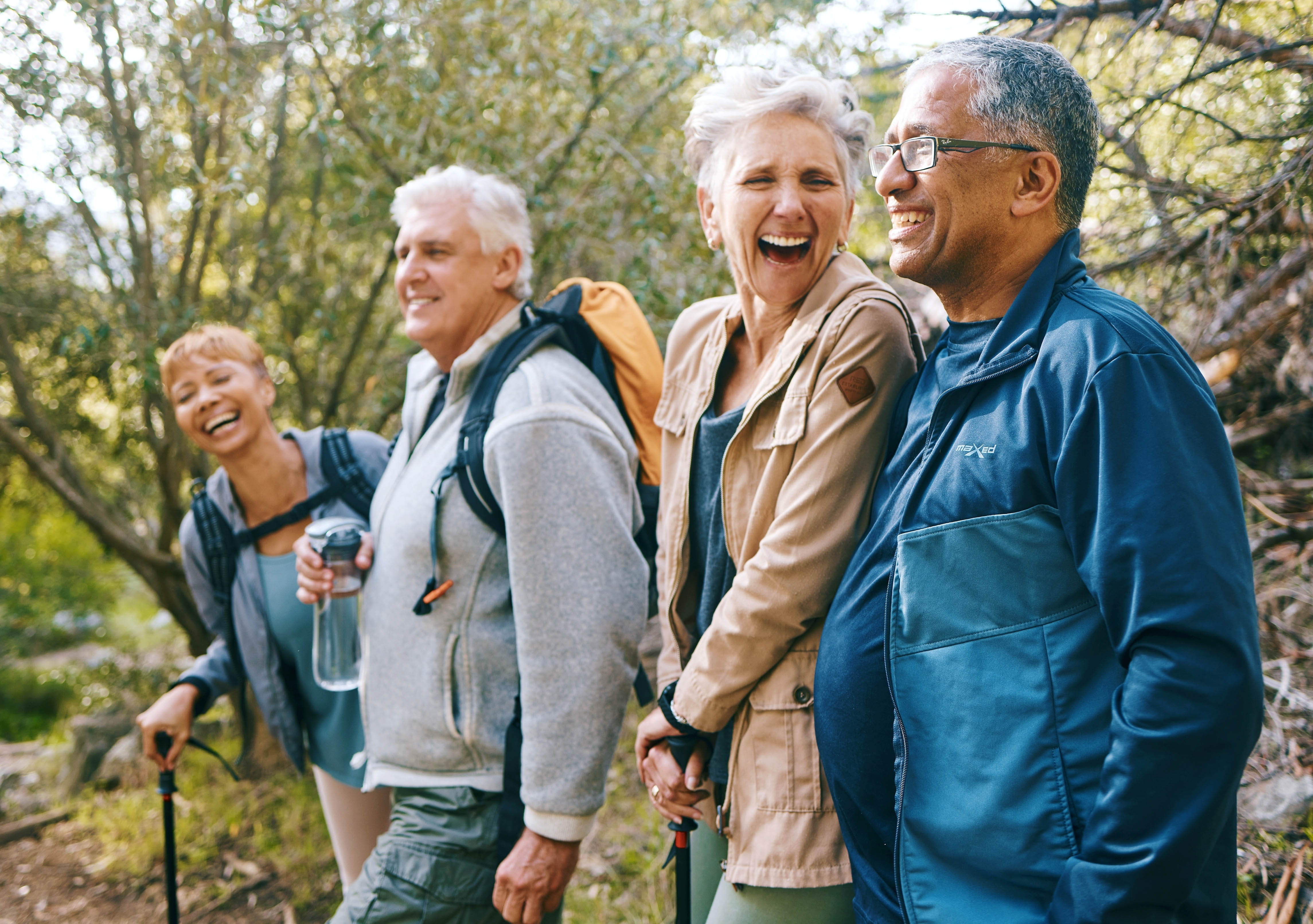 Two older couples hiking outside and smiling together Two older couples hiking outside and smiling together